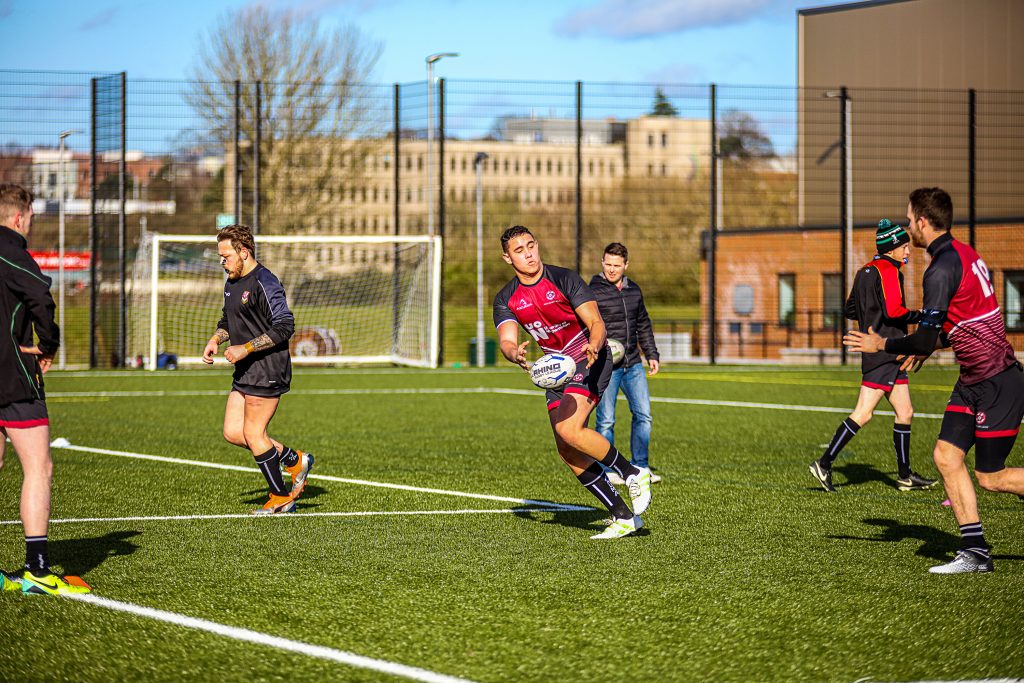 Men playing rugby on artificial turf